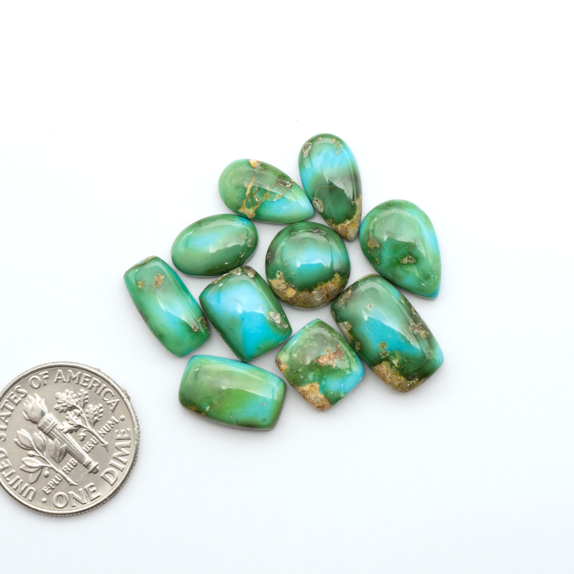 Sonoran Mountain Turquoise cabochons, blue-green color with natural matrix, polished stones on a white background, with a US dime for scale
