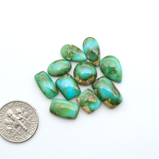 Sonoran Mountain Turquoise cabochons, blue-green color with natural matrix, polished stones on a white background, with a US dime for scale