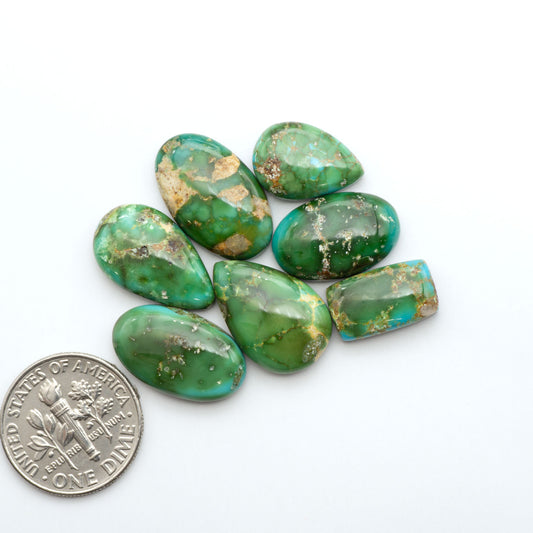 Sonoran Mountain Turquoise cabochons, blue-green color with natural matrix, polished stones on a white background, with a US dime for scale