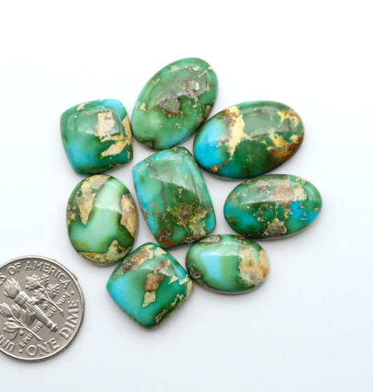 Sonoran Mountain Turquoise cabochons, blue-green color with natural matrix, polished stones on a white background, with a US dime for scale