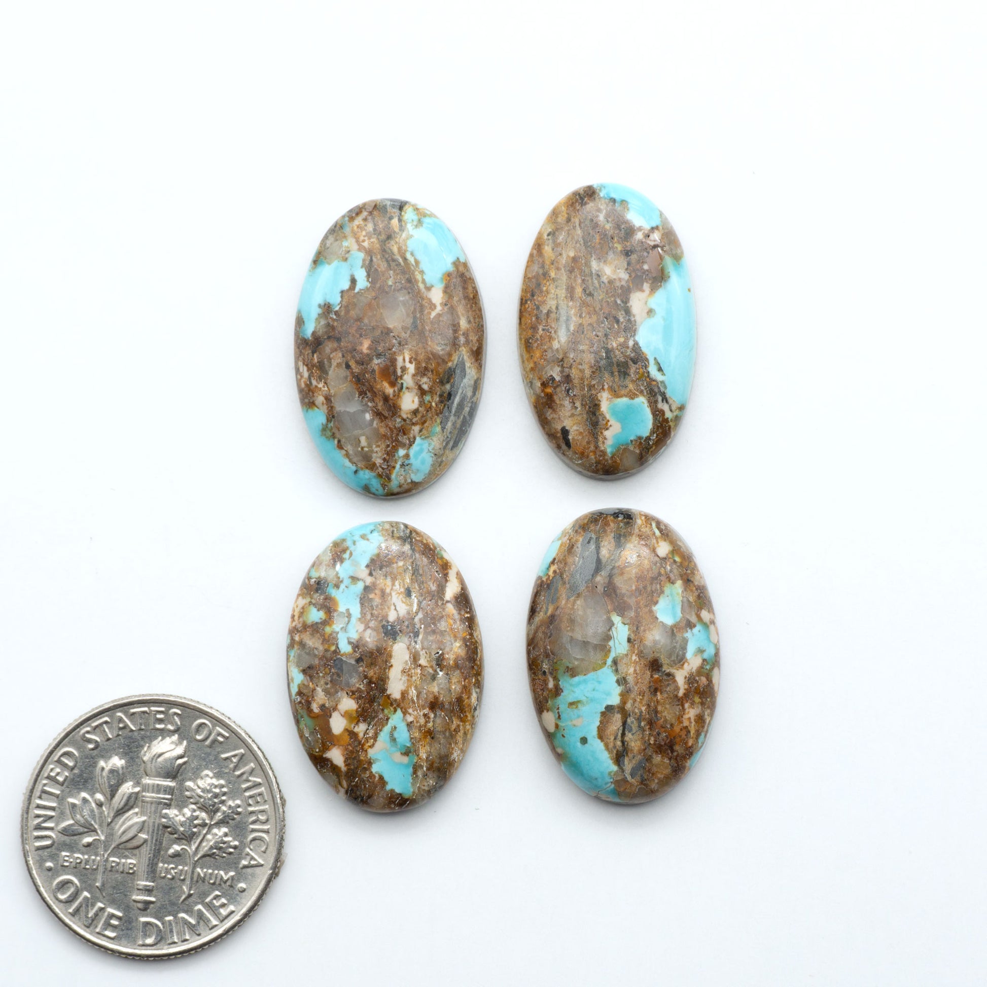 Black Jack turquoise cabochons, blue-green color with black matrix, polished stones on a white background with a US dime for scale