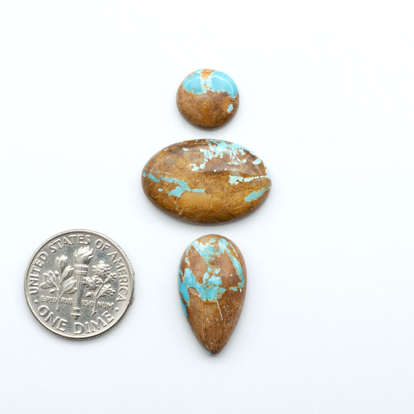 Royston Turquoise cabochons, blue-green color with natural matrix, polished stones on a white background, with a US dime for scale