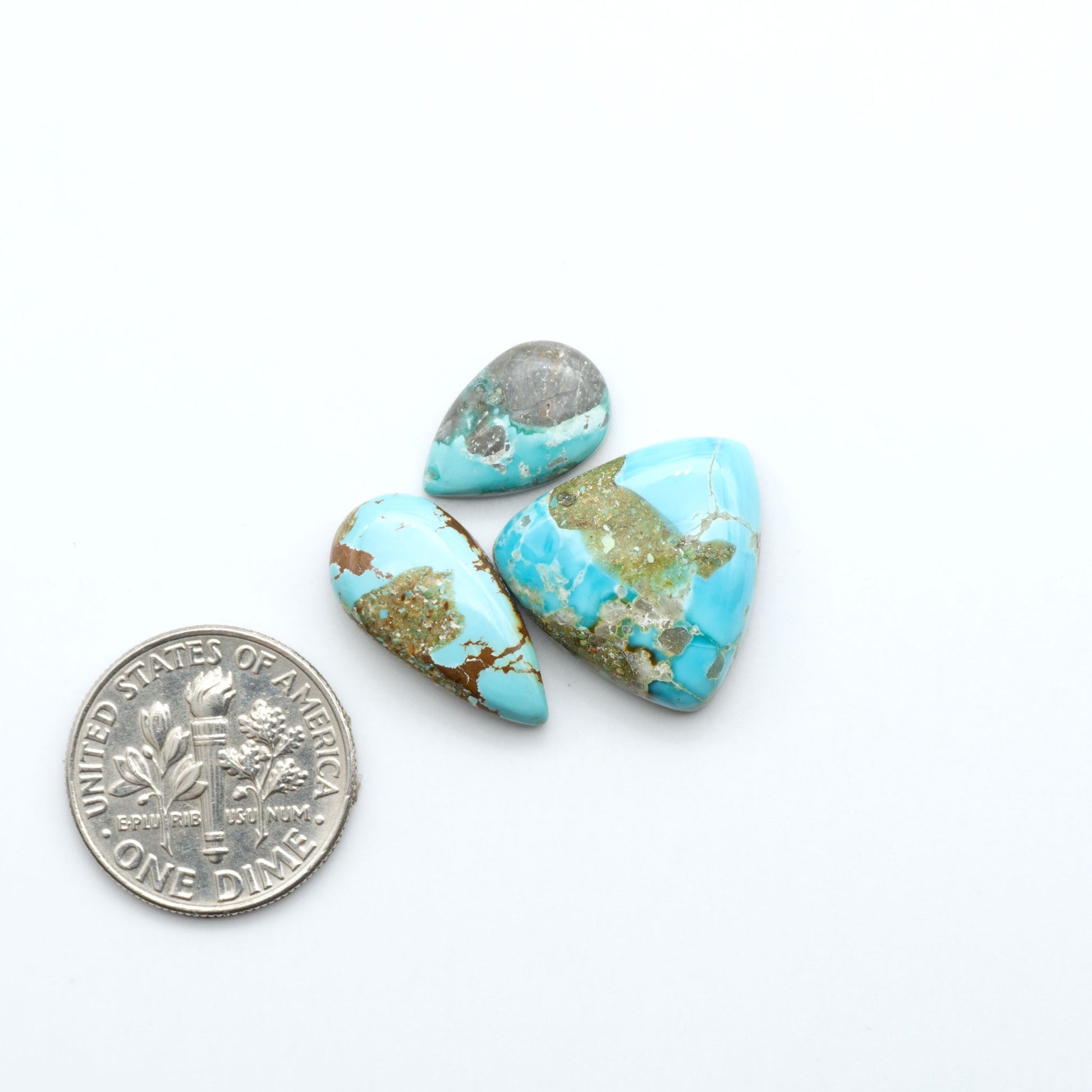 Royston Turquoise cabochons, blue-green color with natural matrix, polished stones on a white background, with a US dime for scale