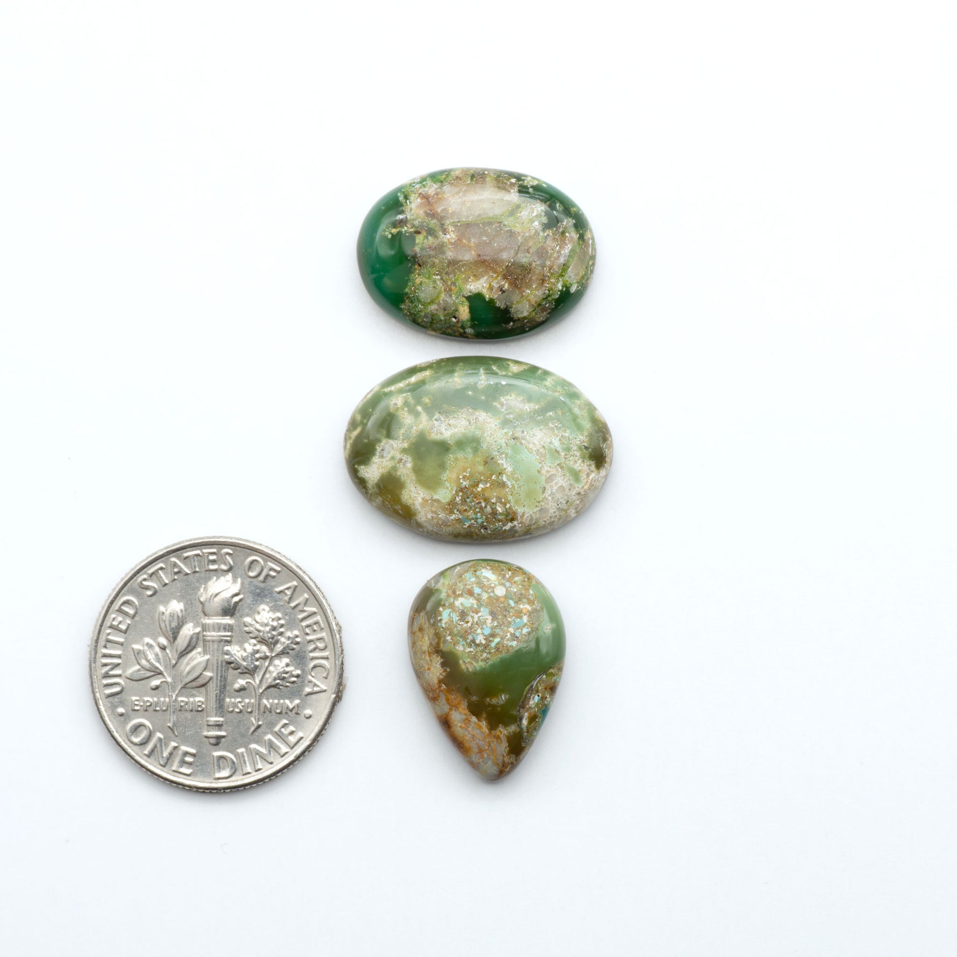 Royston Turquoise cabochons, blue-green color with natural matrix, polished stones on a white background, with a US dime for scale
