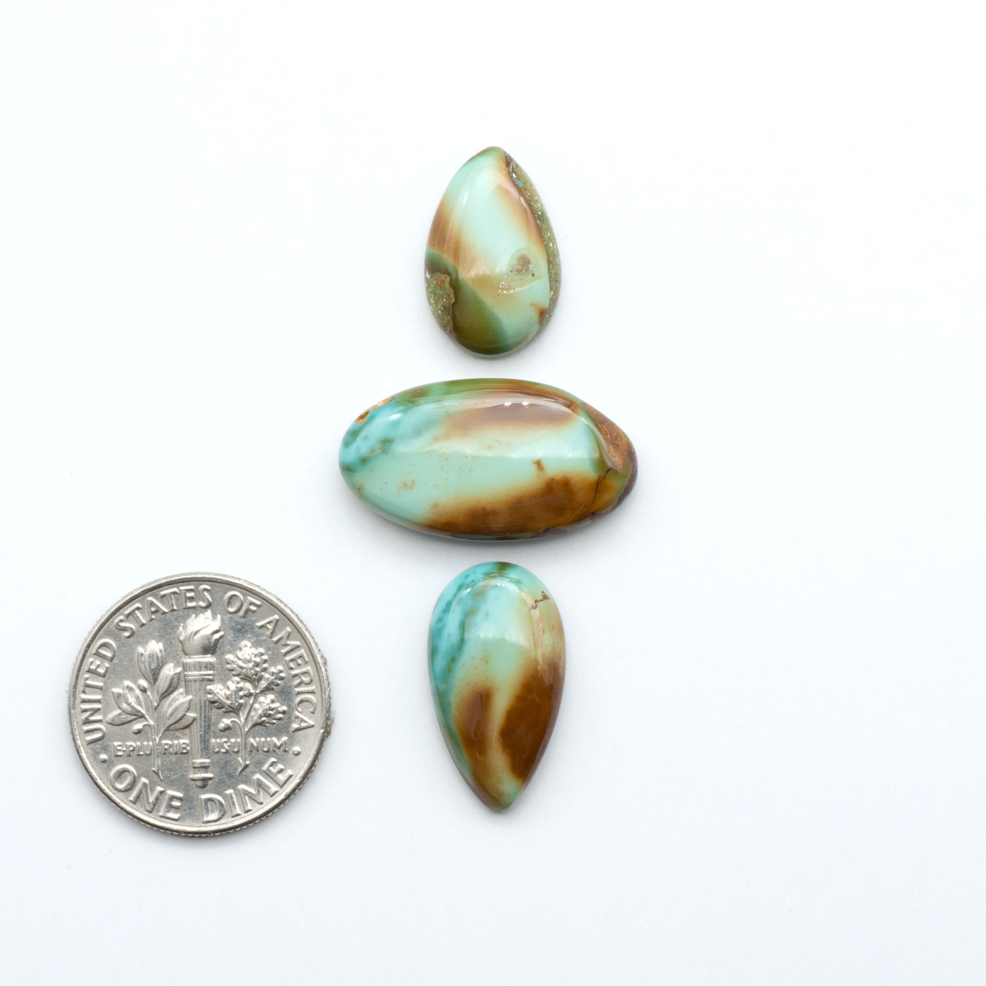 Royston Turquoise cabochons, blue-green color with natural matrix, polished stones on a white background, with a US dime for scale