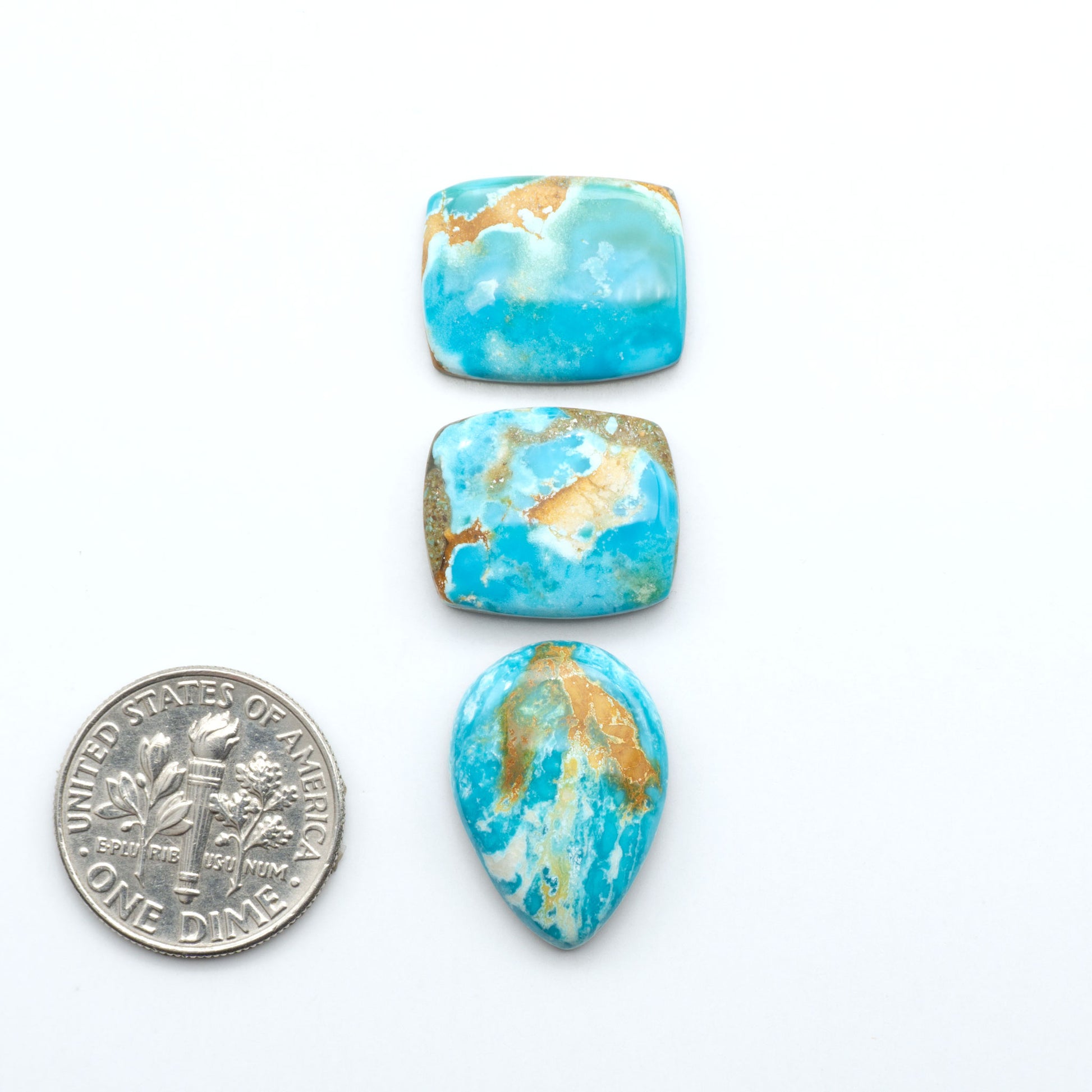Royston Turquoise cabochons, blue-green color with natural matrix, polished stones on a white background, with a US dime for scale