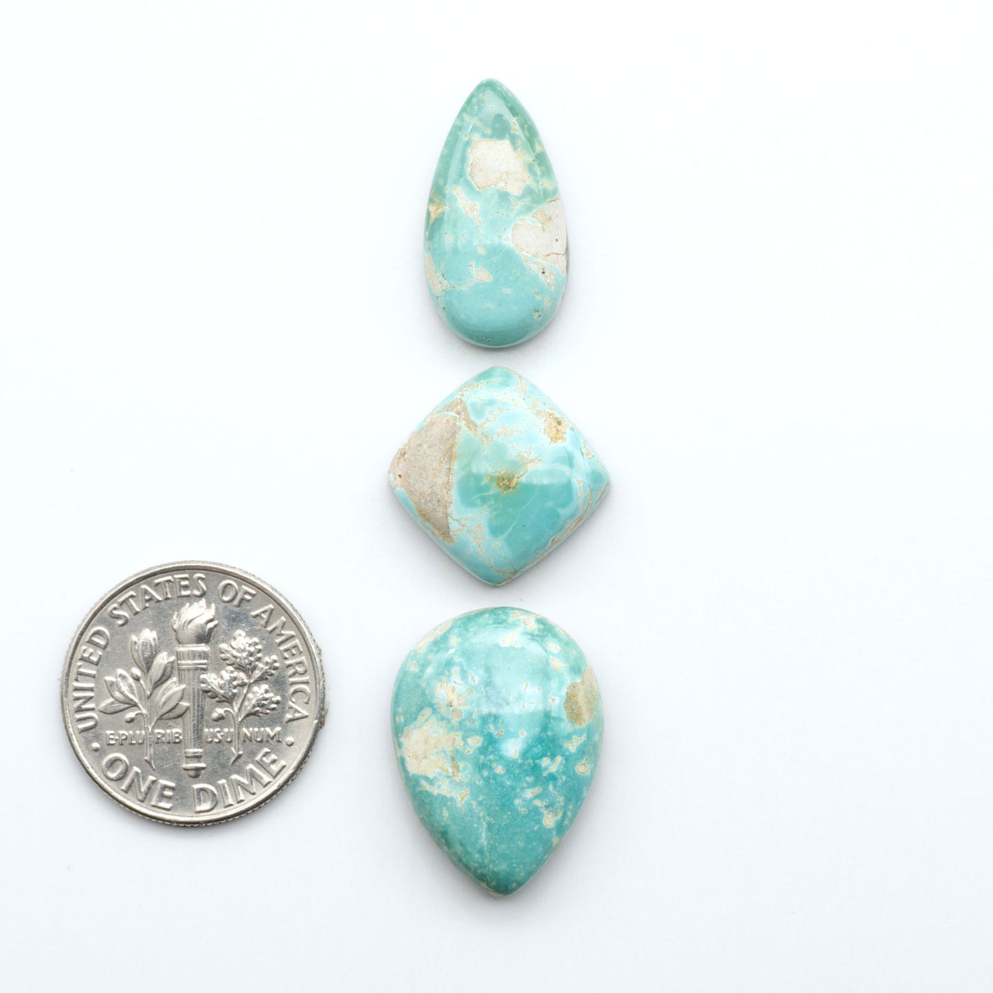 Royston Turquoise cabochons, blue-green color with natural matrix, polished stones on a white background, with a US dime for scale