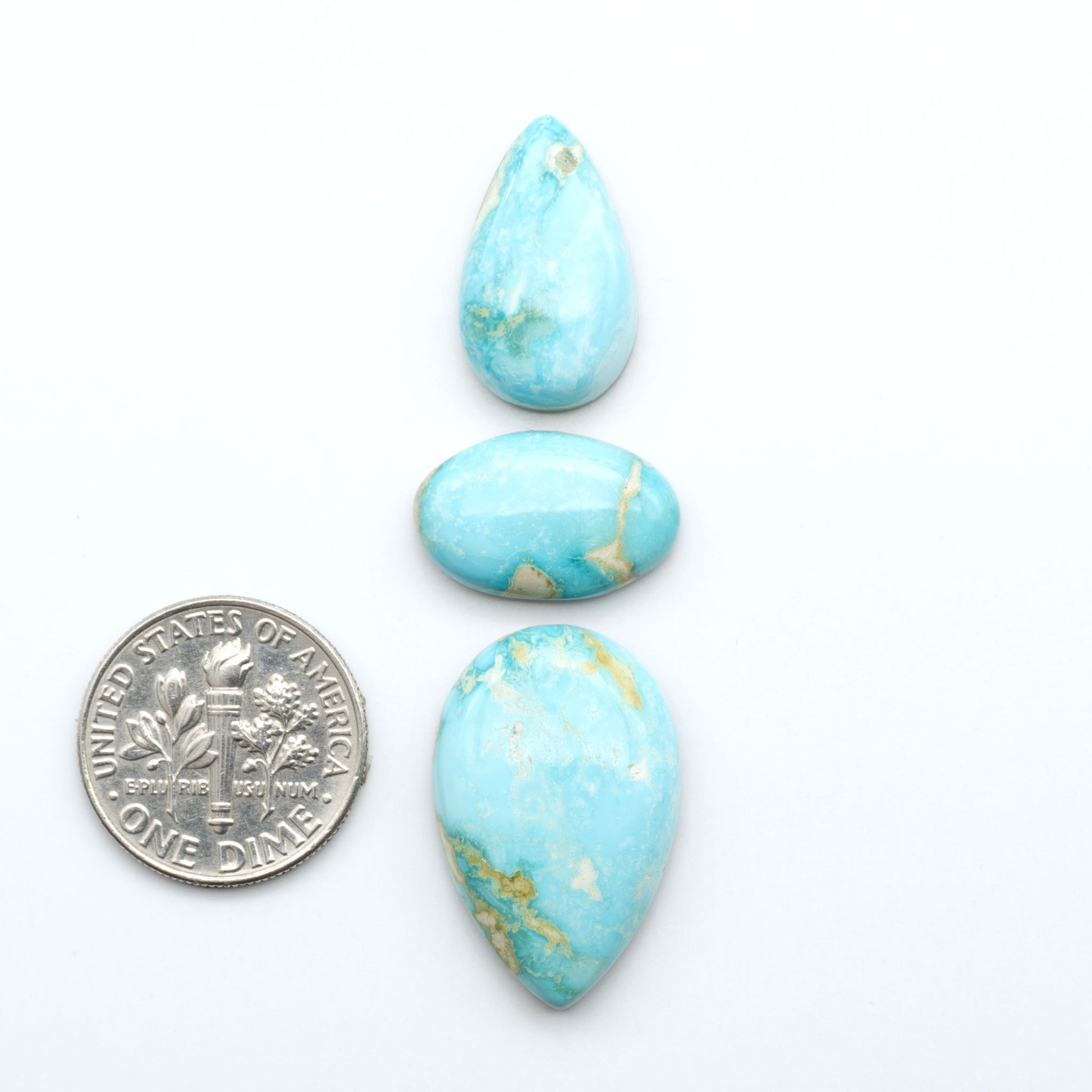 Royston Turquoise cabochons, blue-green color with natural matrix, polished stones on a white background, with a US dime for scale