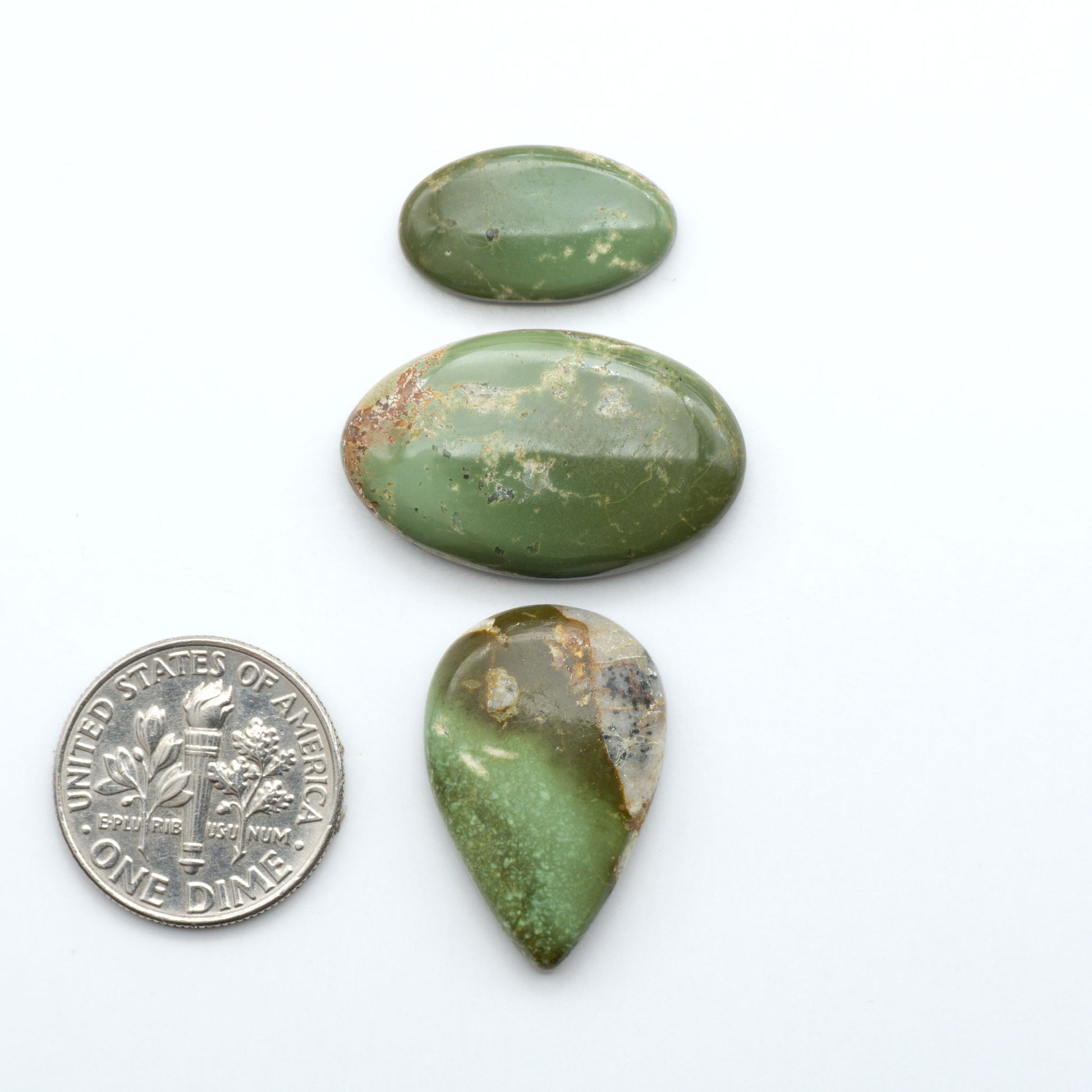 Royston Turquoise cabochons, blue-green color with natural matrix, polished stones on a white background, with a US dime for scale