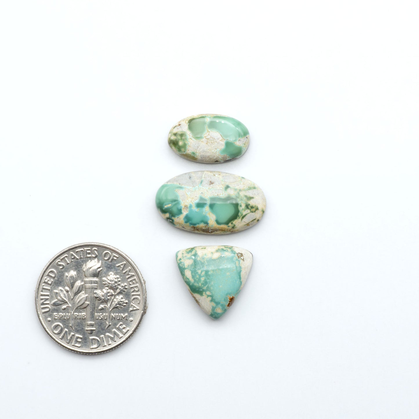 Royston Turquoise cabochons, blue-green color with natural matrix, polished stones on a white background, with a US dime for scale