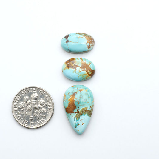 Royston Turquoise cabochons, blue-green color with natural matrix, polished stones on a white background, with a US dime for scale