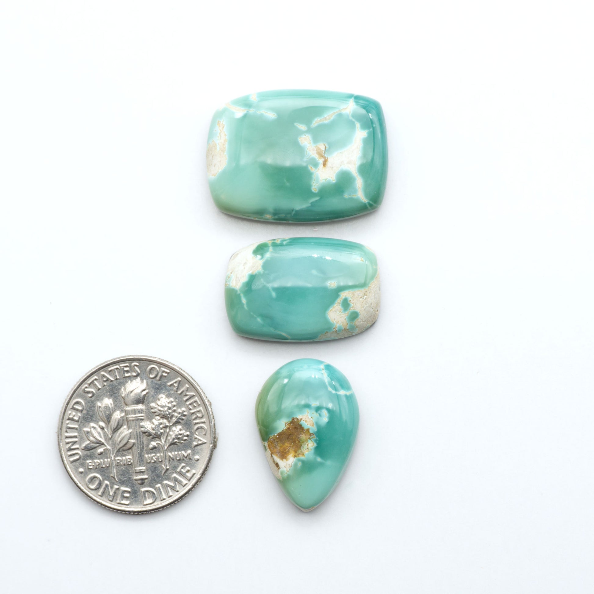 Royston Turquoise cabochons, blue-green color with natural matrix, polished stones on a white background, with a US dime for scale