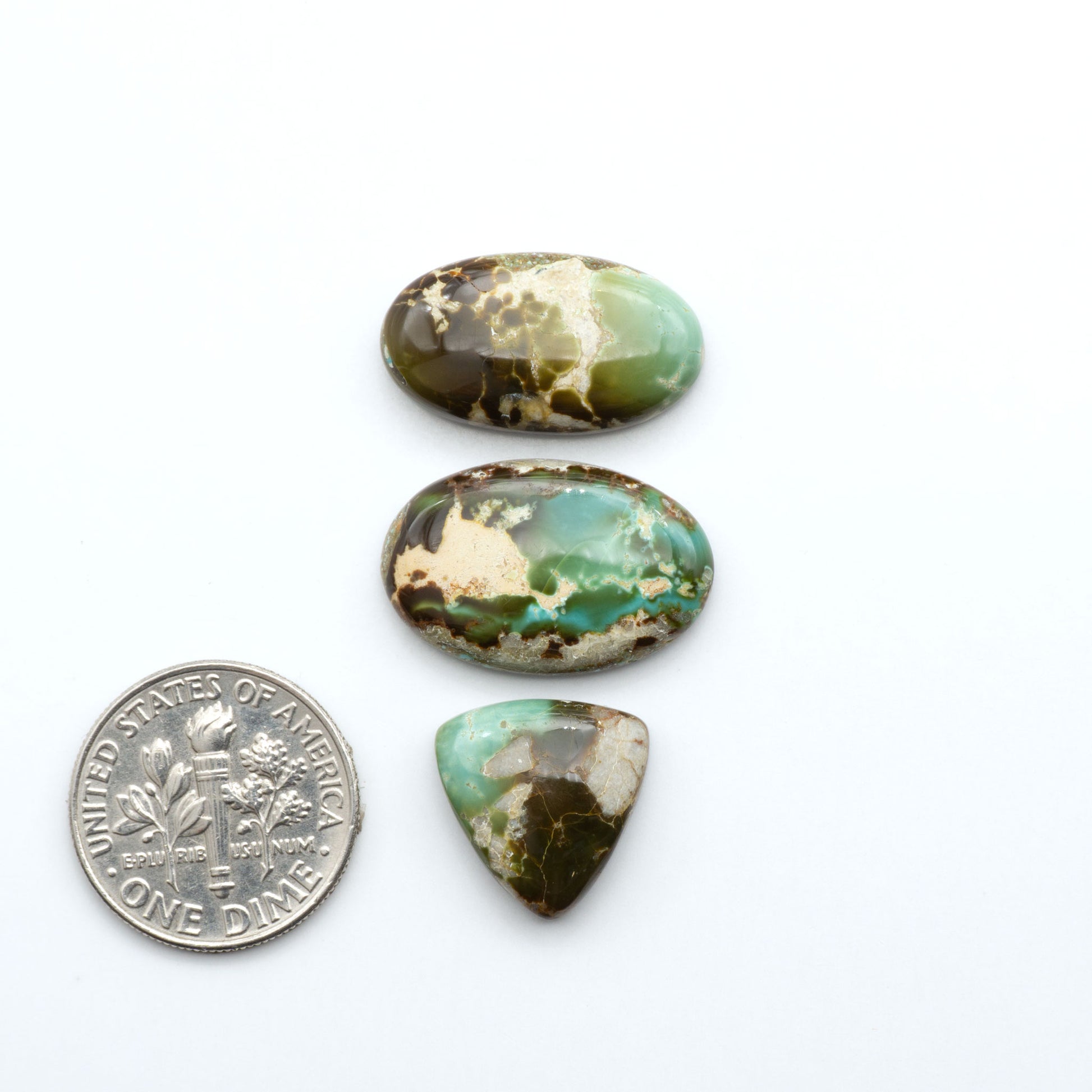 Royston Turquoise cabochons, blue-green color with natural matrix, polished stones on a white background, with a US dime for scale