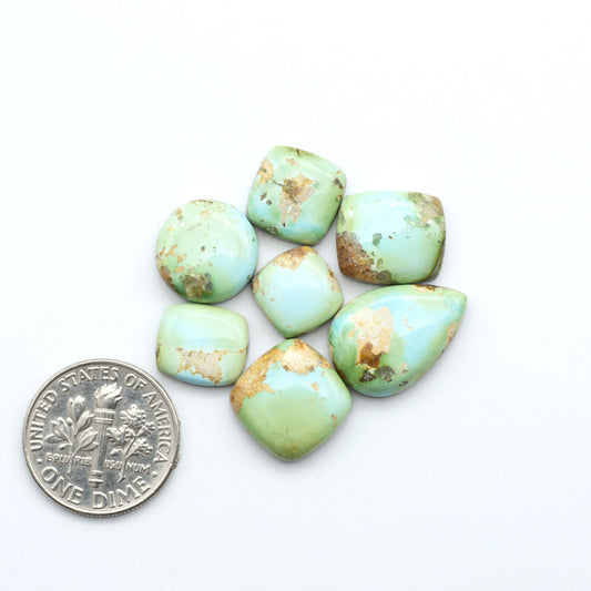 Sonoran Mountain Turquoise cabochons, blue-green color with natural matrix, polished stones on a white background, with a US dime for scale