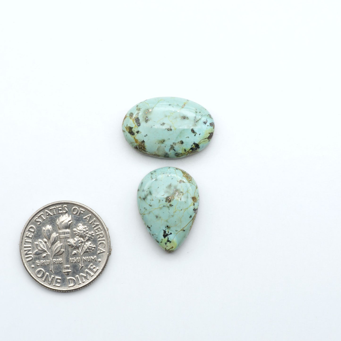Sonoran Mountain Turquoise cabochons, blue-green color with natural matrix, polished stones on a white background, with a US dime for scale