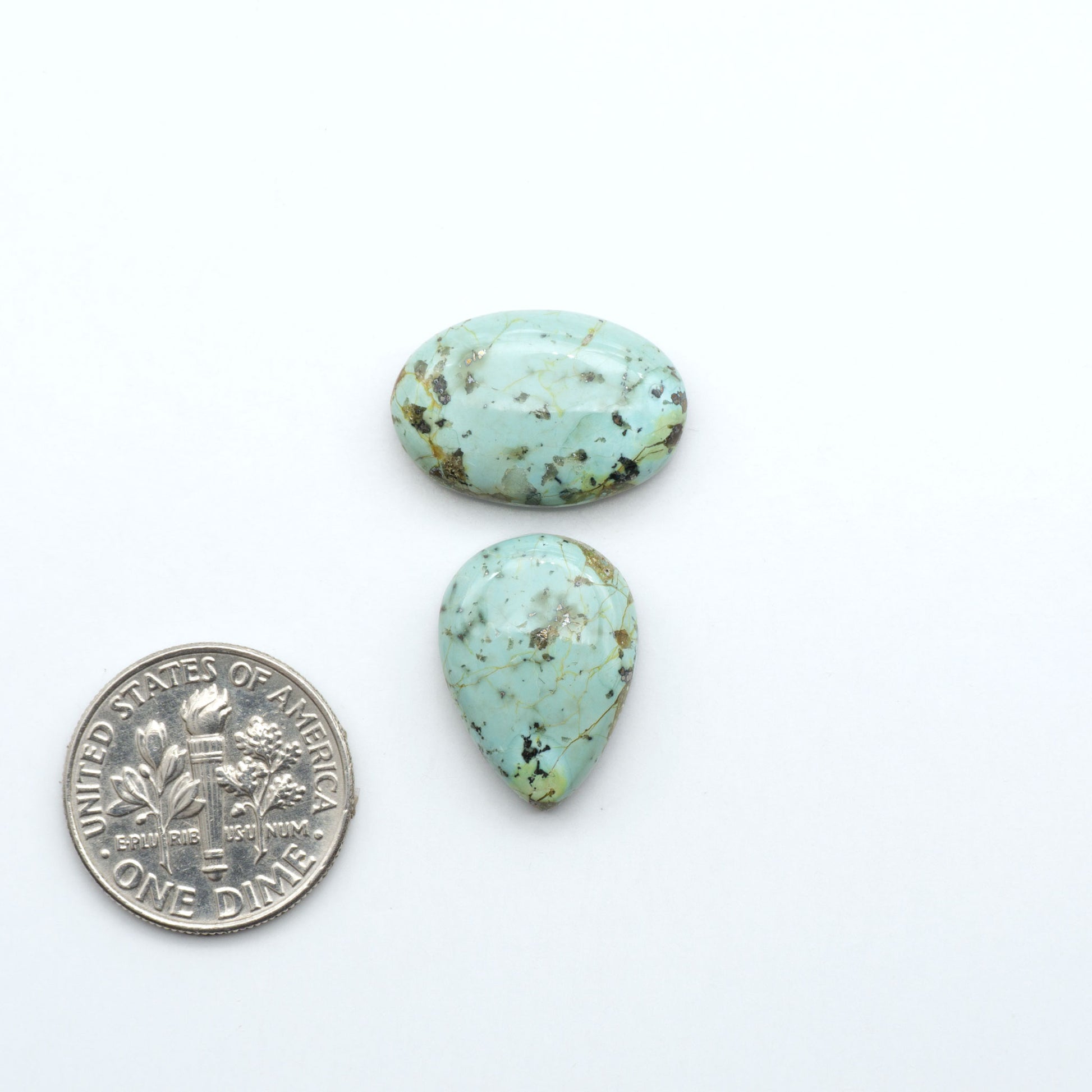 Sonoran Mountain Turquoise cabochons, blue-green color with natural matrix, polished stones on a white background, with a US dime for scale