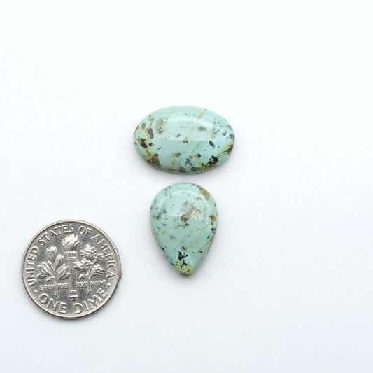 Sonoran Mountain Turquoise cabochons, blue-green color with natural matrix, polished stones on a white background, with a US dime for scale