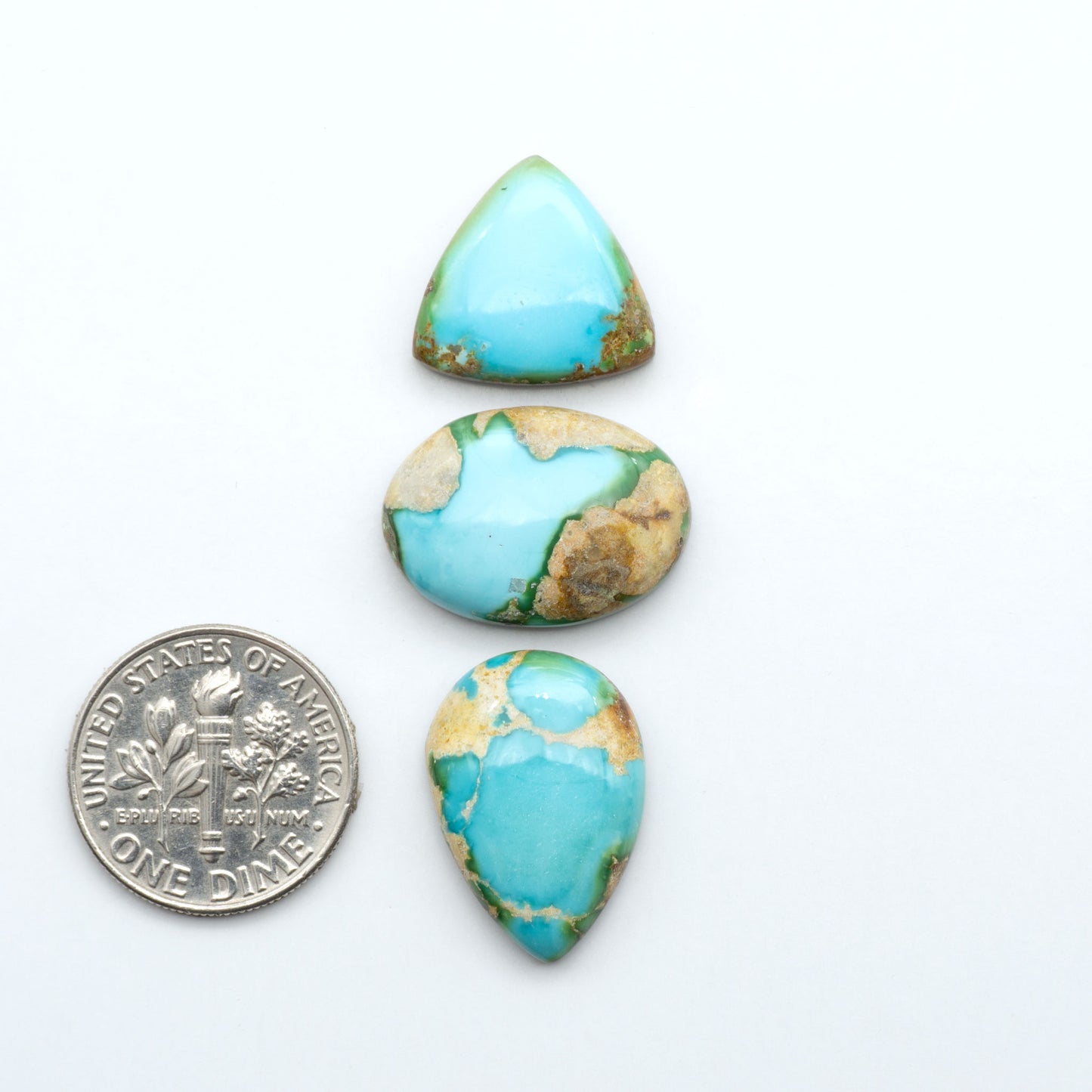 Sonoran Mountain Turquoise cabochons, blue-green color with natural matrix, polished stones on a white background, with a US dime for scale