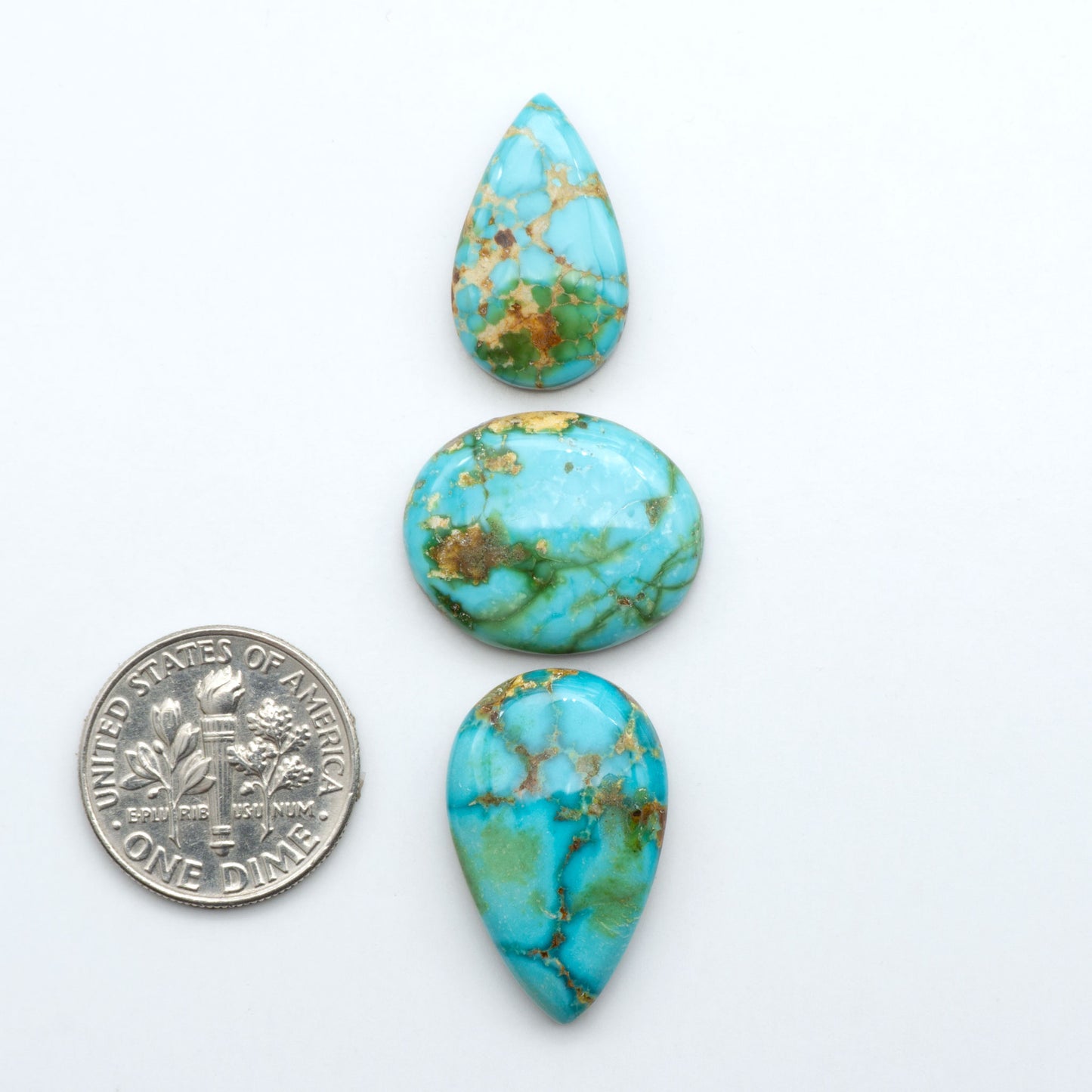Sonoran Mountain Turquoise cabochons, blue-green color with natural matrix, polished stones on a white background, with a US dime for scale