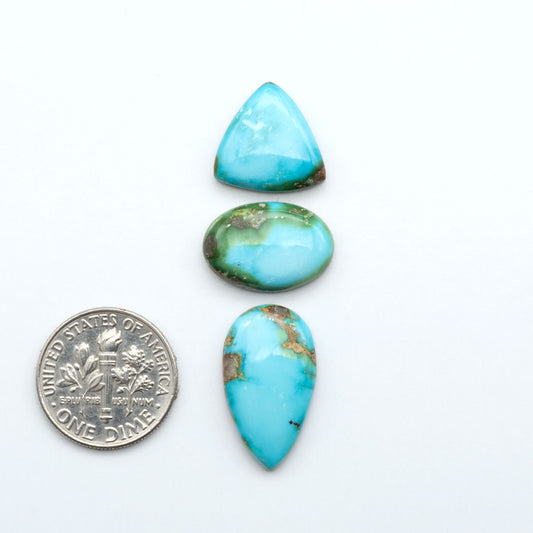 Sonoran Mountain Turquoise cabochons, blue-green color with natural matrix, polished stones on a white background, with a US dime for scale