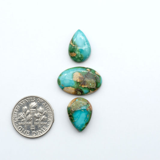Sonoran Mountain Turquoise cabochons, blue-green color with natural matrix, polished stones on a white background, with a US dime for scale