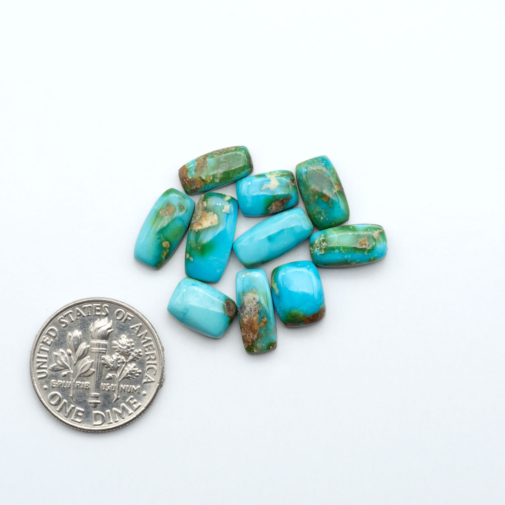 Sonoran Mountain Turquoise cabochons, blue-green color with natural matrix, polished stones on a white background, with a US dime for scale