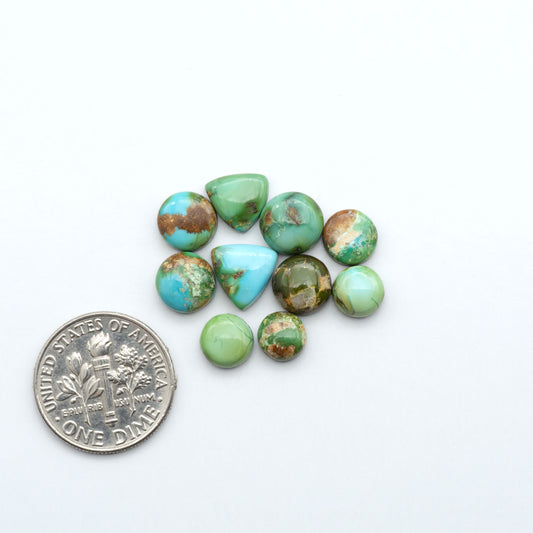 Sonoran Mountain Turquoise cabochons, blue-green color with natural matrix, polished stones on a white background, with a US dime for scale