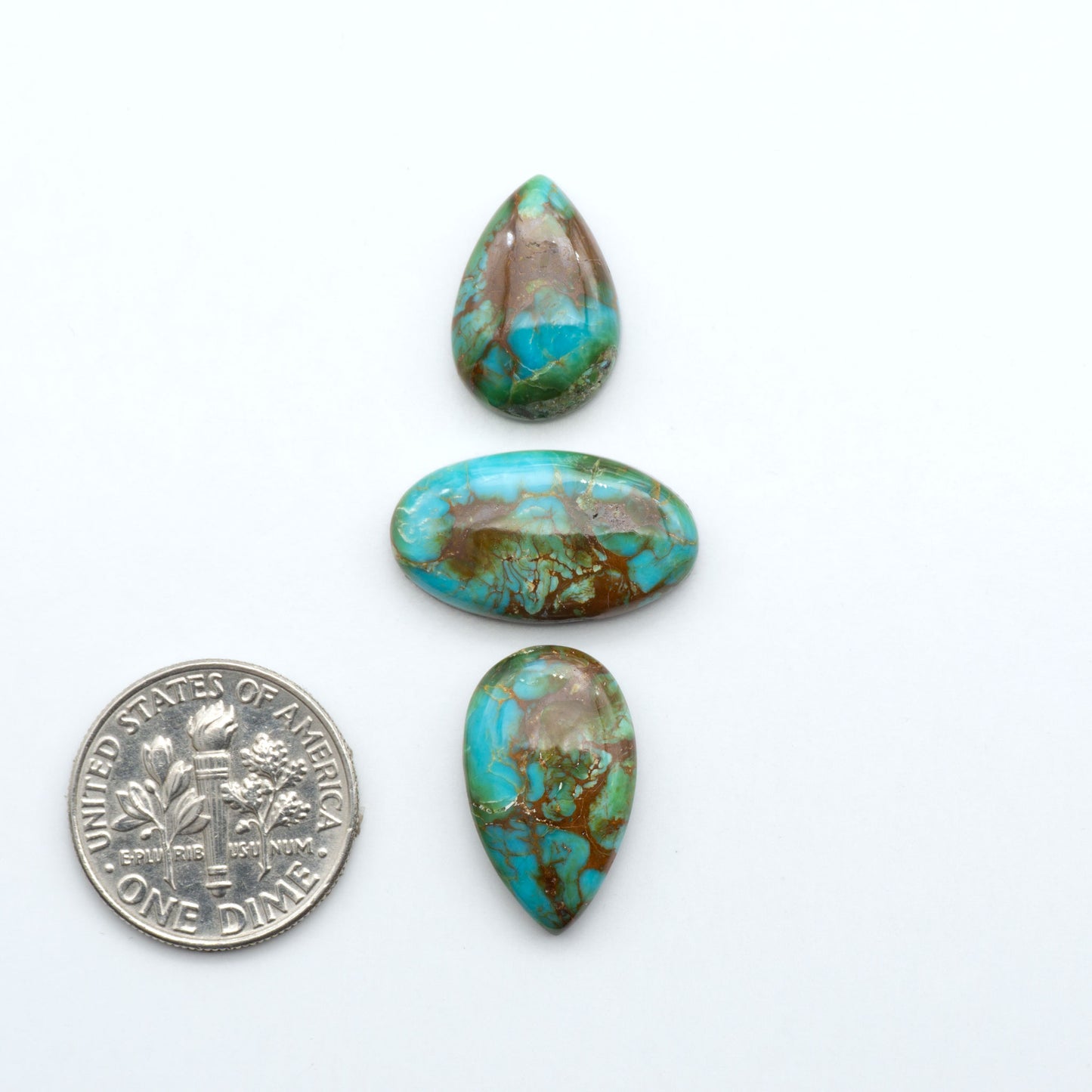 Sonoran Mountain Turquoise cabochons, blue-green color with natural matrix, polished stones on a white background, with a US dime for scale
