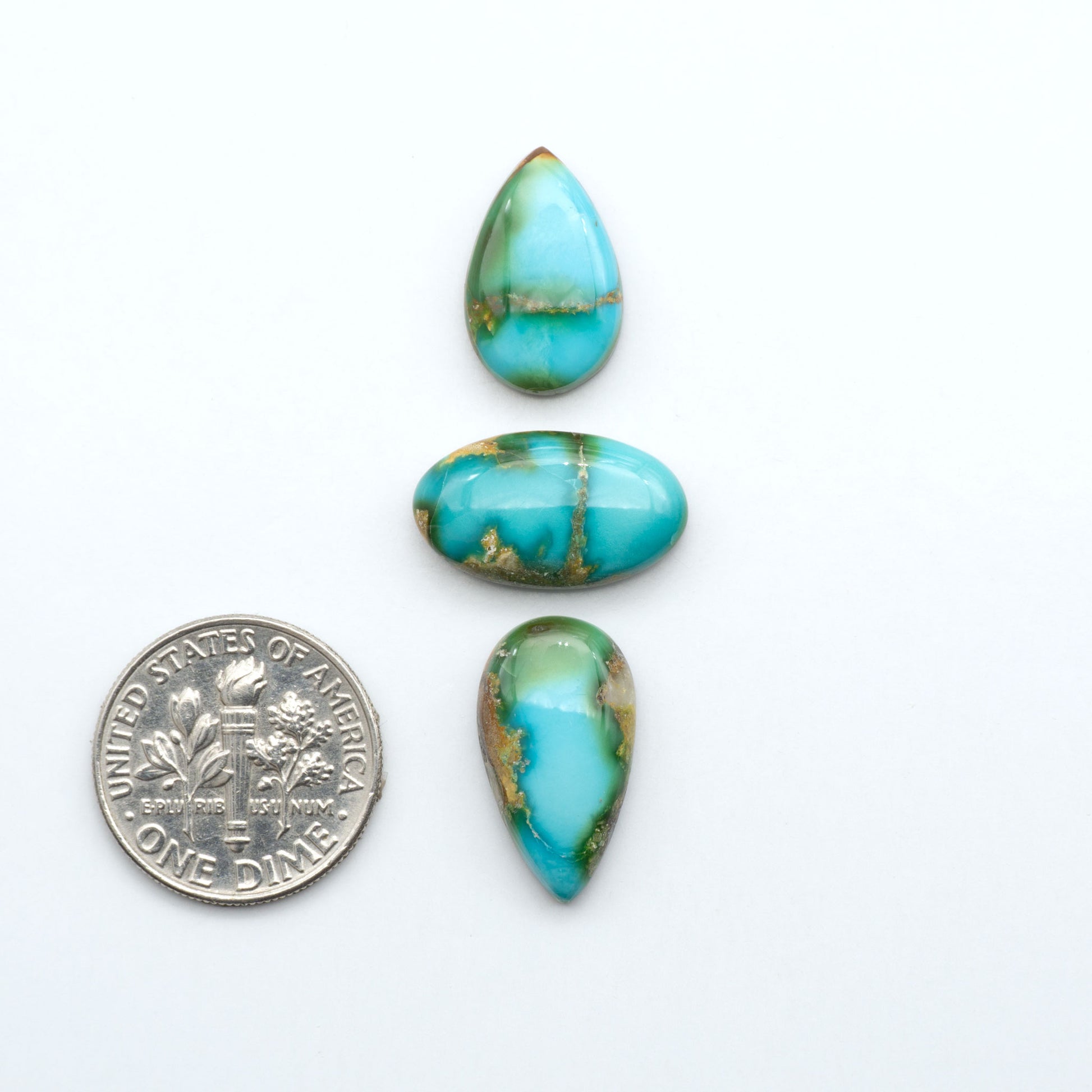 Sonoran Mountain Turquoise cabochons, blue-green color with natural matrix, polished stones on a white background, with a US dime for scale