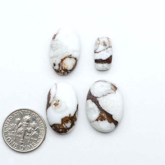Wild Horse Magnesite cabochons, white gemstones with brown matrix on a white background, with a US dime for scale
