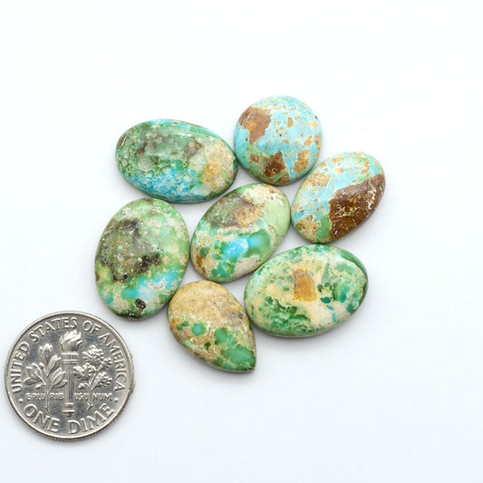 Sonoran Mountain Turquoise cabochons, blue-green color with natural matrix, polished stones on a white background, with a US dime for scale
