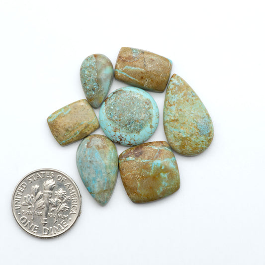 Number 8 Turquoise cabochons, blue and green color with brown matrix, polished stones on a white background, with a US dime for scale