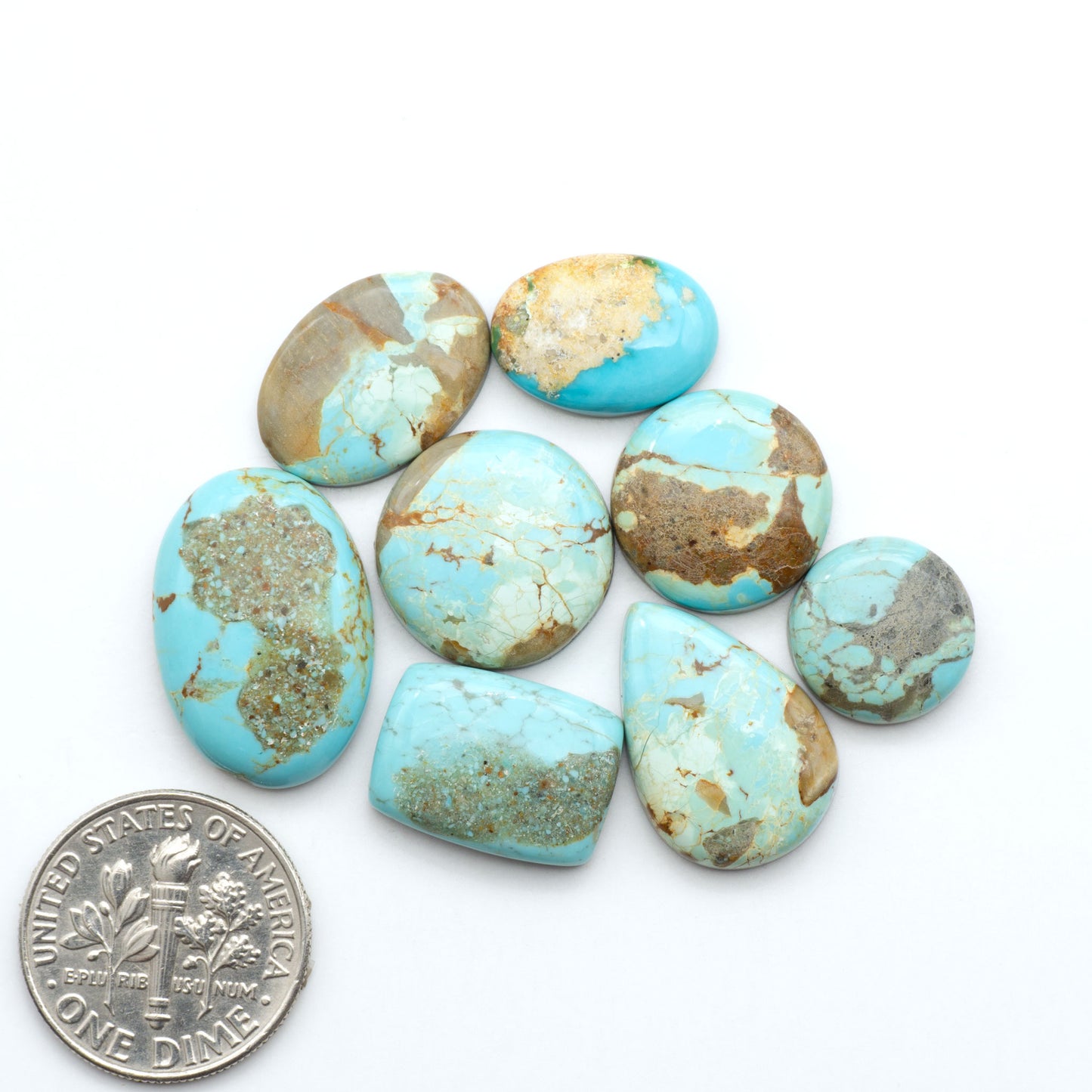 Number 8 Turquoise cabochons, blue and green color with brown matrix, polished stones on a white background, with a US dime for scale