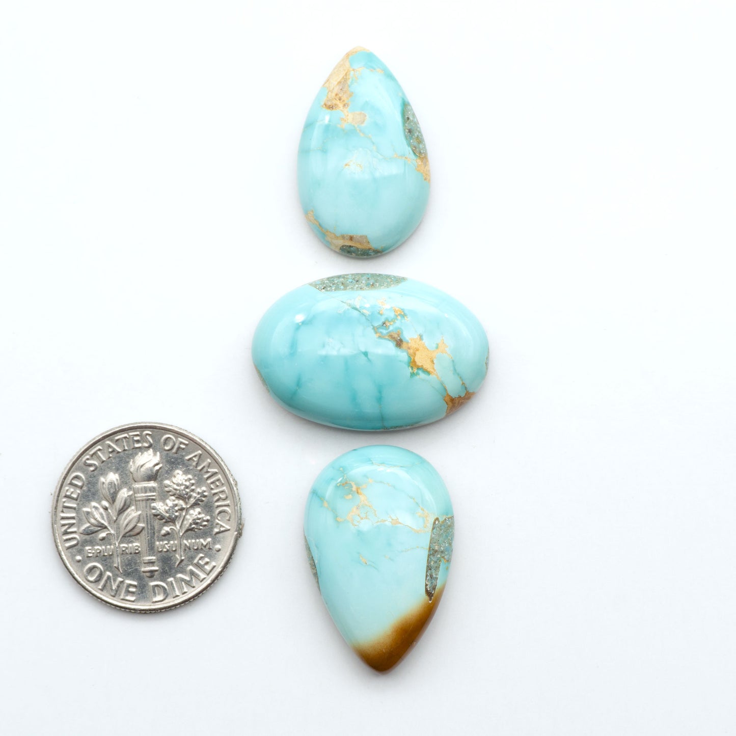 Royston Turquoise cabochons, blue-green color with natural matrix, polished stones on a white background, with a US dime for scale