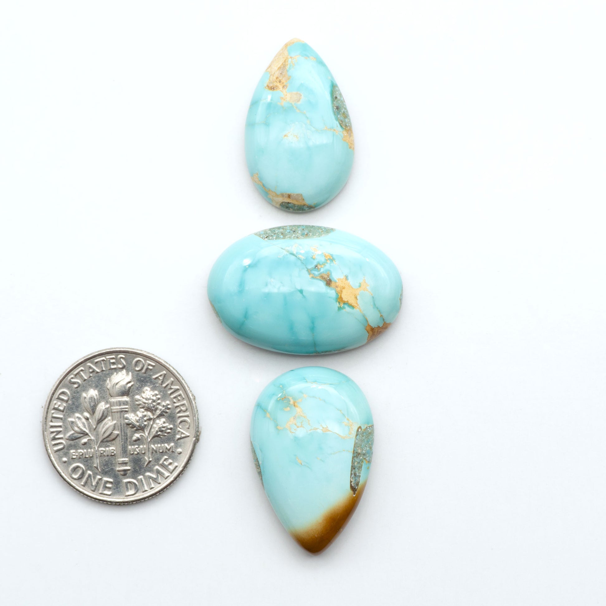 Royston Turquoise cabochons, blue-green color with natural matrix, polished stones on a white background, with a US dime for scale