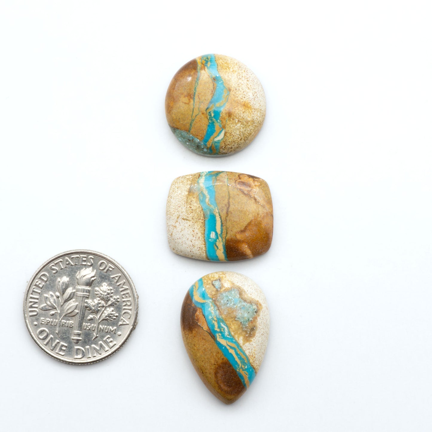 Royston Turquoise cabochons, blue-green color with natural matrix, polished stones on a white background, with a US dime for scale