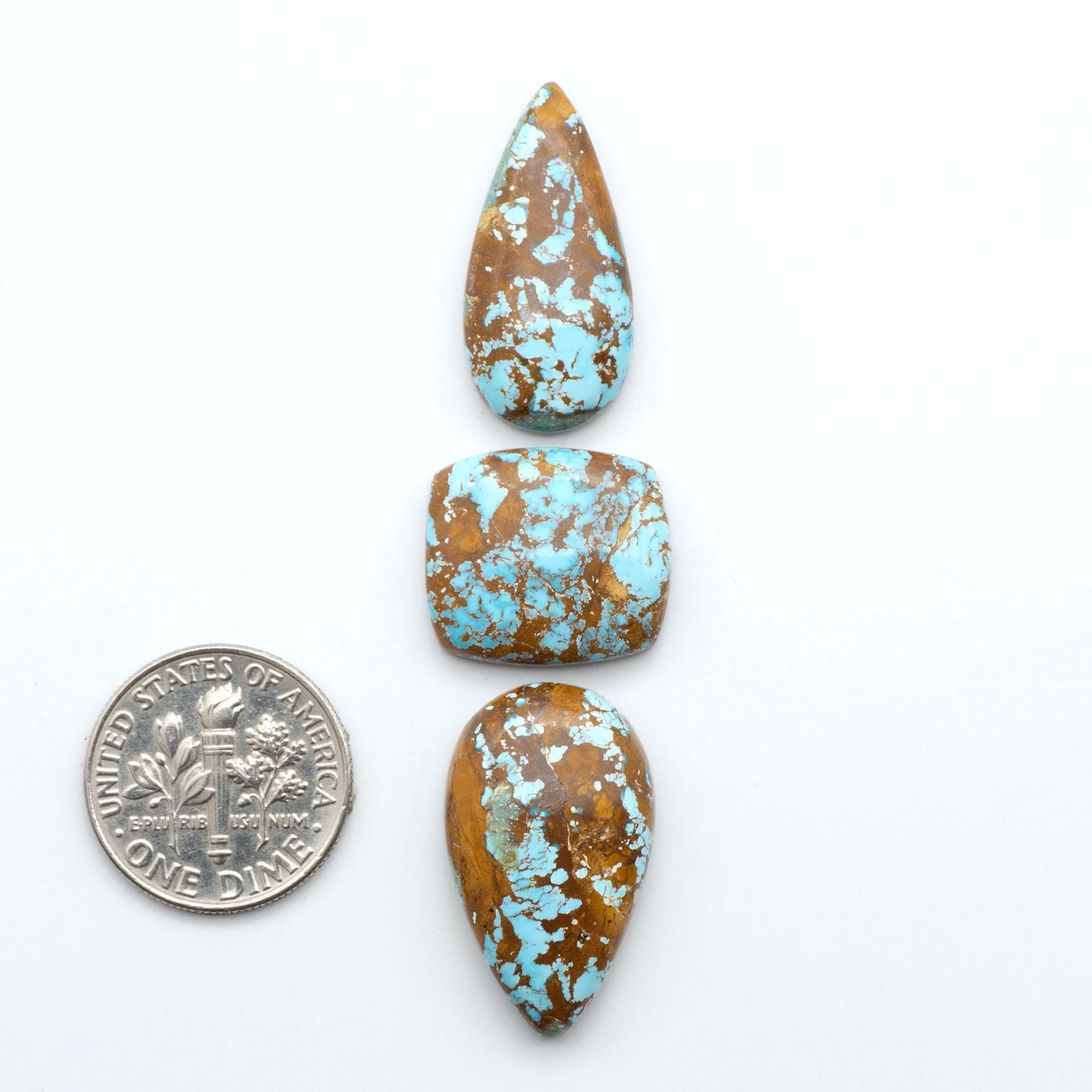 Royston Turquoise cabochons, blue-green color with natural matrix, polished stones on a white background, with a US dime for scale