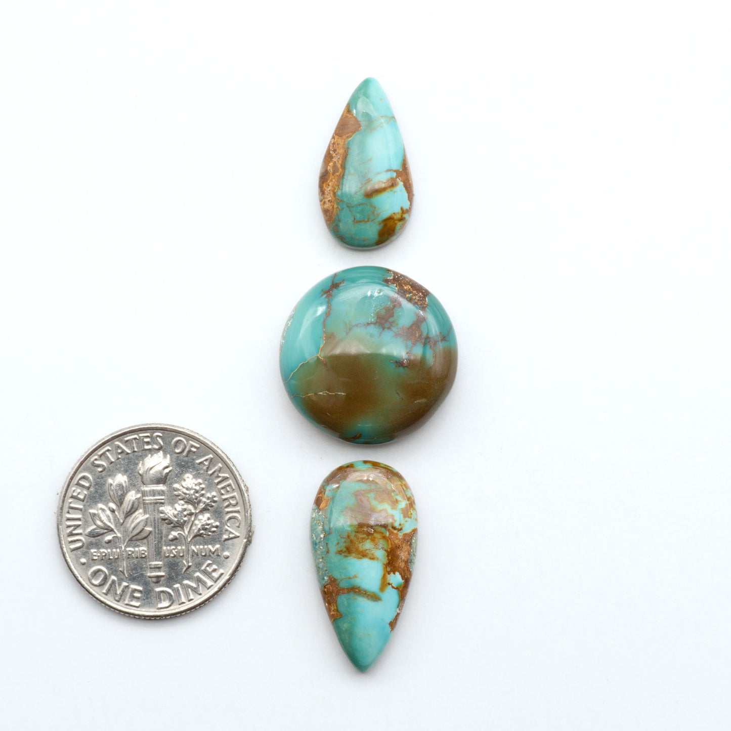 Royston Turquoise cabochons, blue-green color with natural matrix, polished stones on a white background, with a US dime for scale
