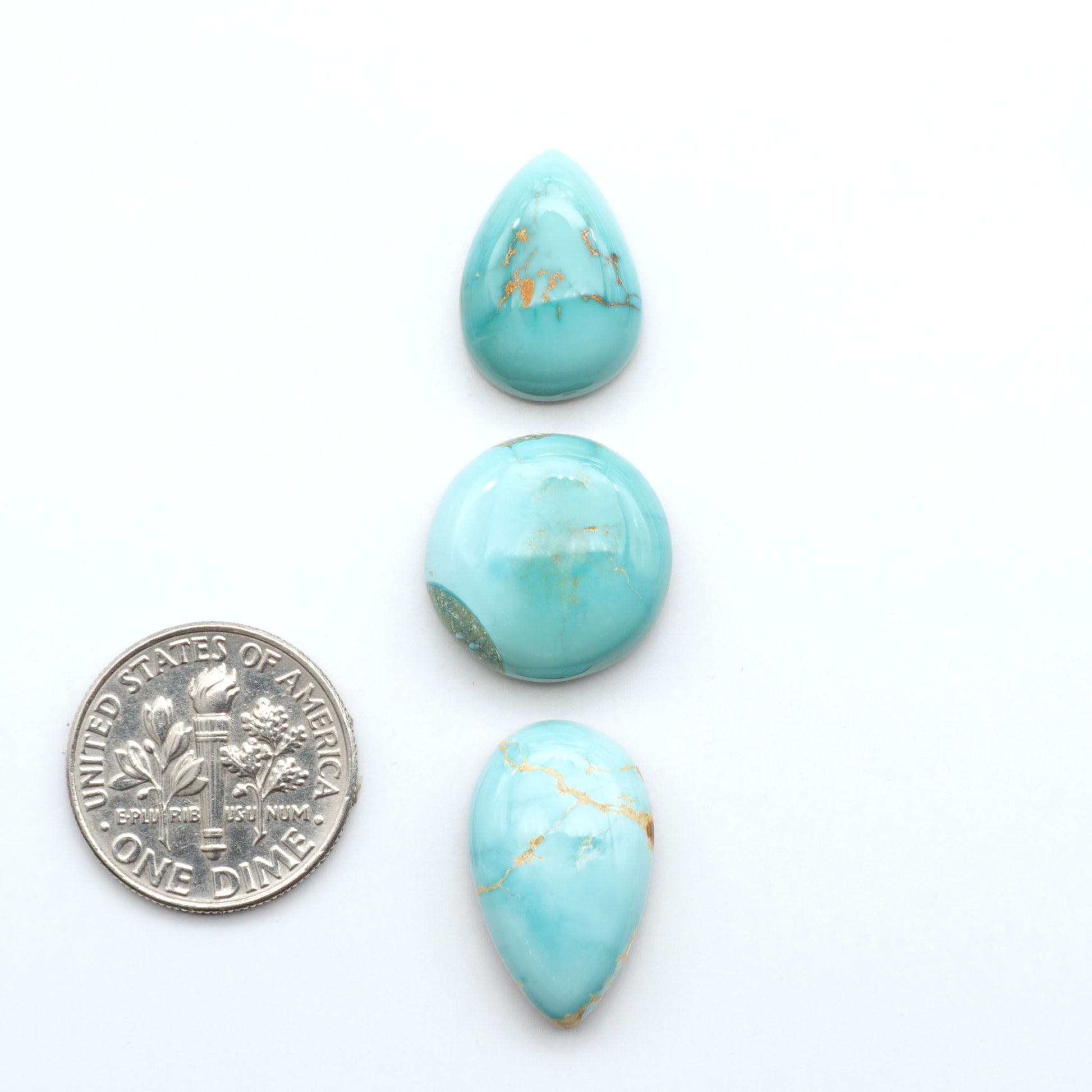 Royston Turquoise cabochons, blue-green color with natural matrix, polished stones on a white background, with a US dime for scale
