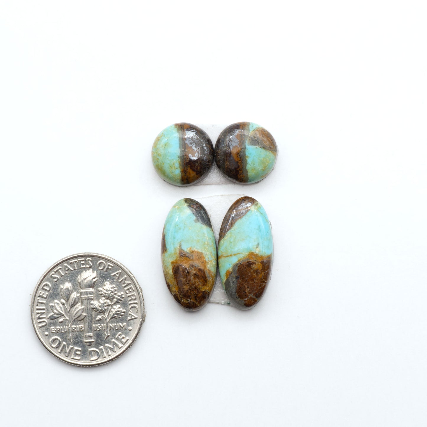 Number 8 Turquoise cabochons, blue and green color with brown matrix, polished stones on a white background, with a US dime for scale