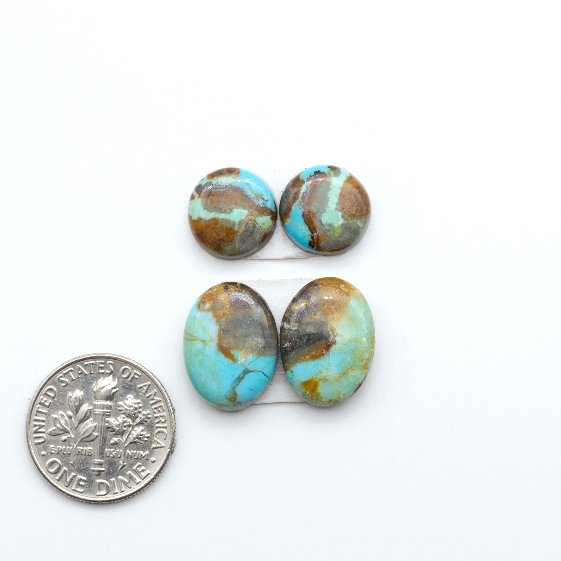 Number 8 Turquoise cabochons, blue and green color with brown matrix, polished stones on a white background, with a US dime for scale