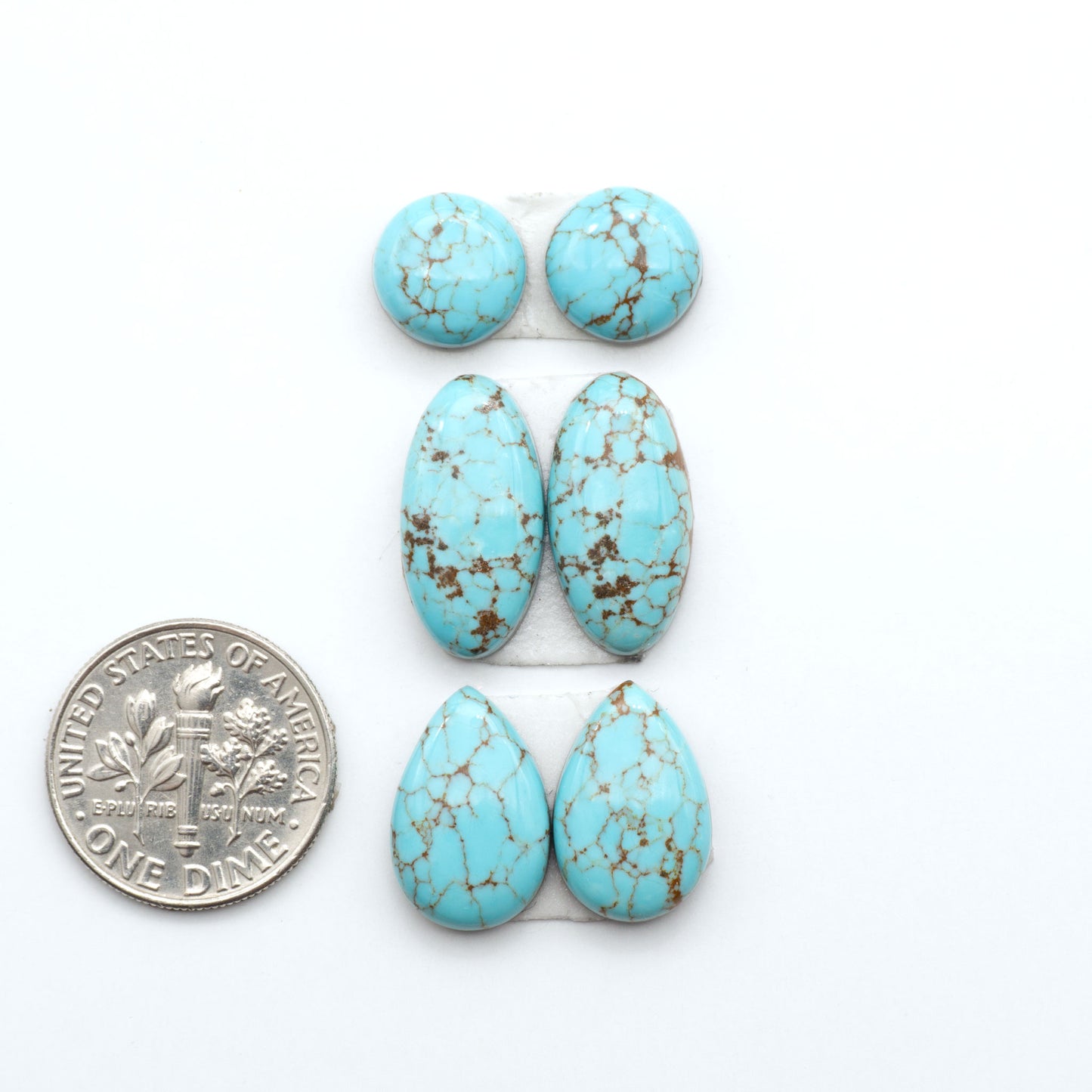 Number 8 Turquoise cabochons, blue and green color with brown matrix, polished stones on a white background, with a US dime for scale
