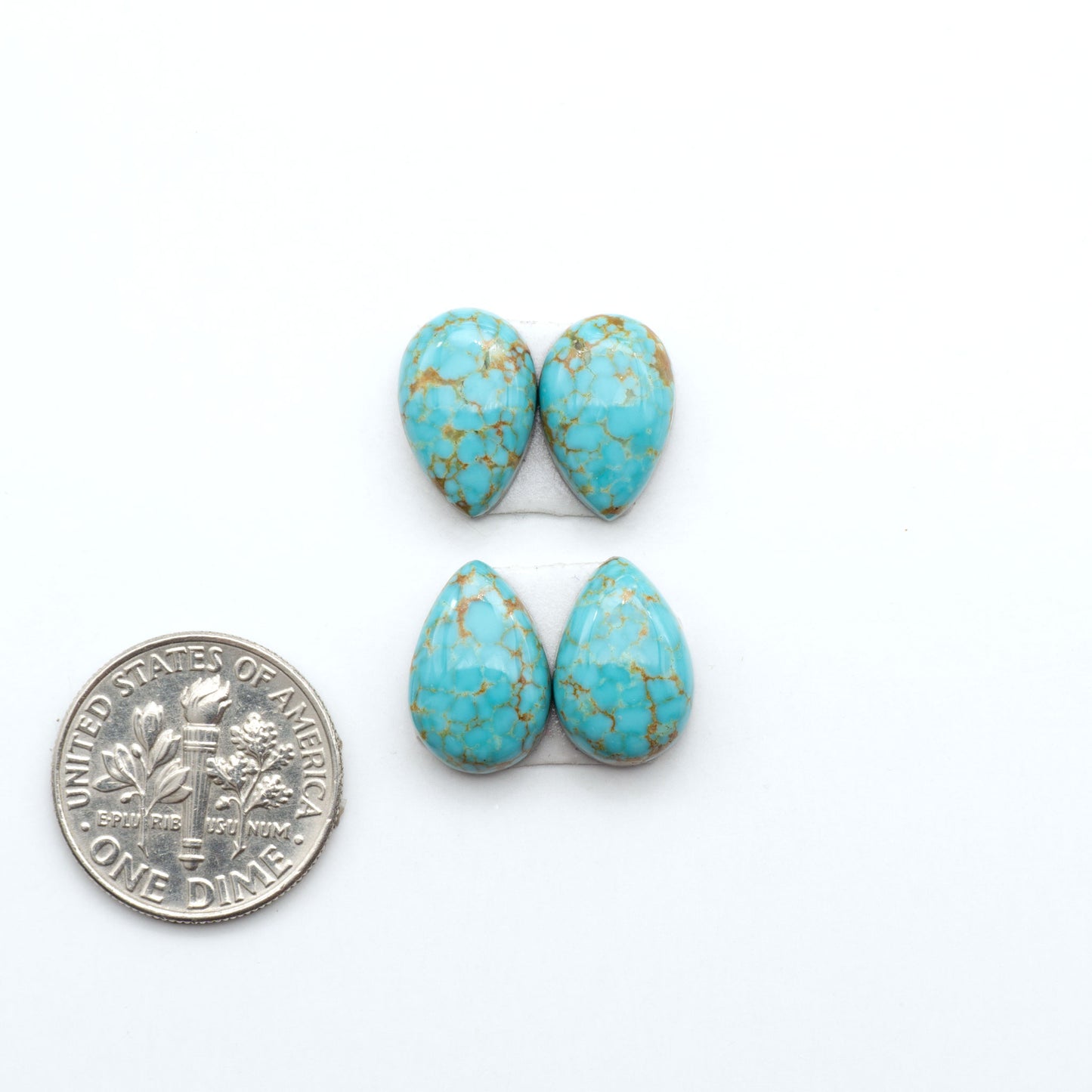 Number 8 Turquoise cabochons, blue and green color with brown matrix, polished stones on a white background, with a US dime for scale