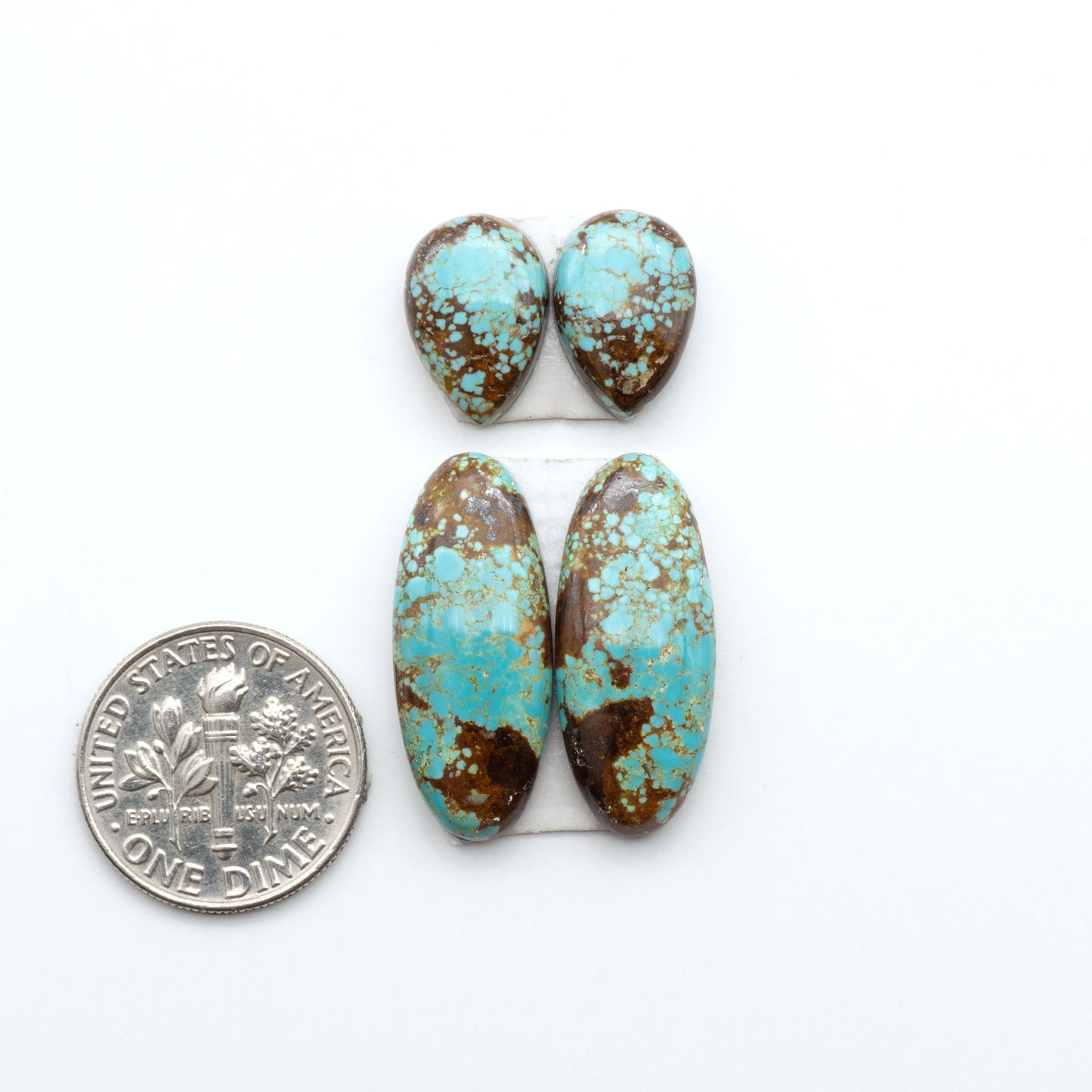 Number 8 Turquoise cabochons, blue and green color with brown matrix, polished stones on a white background, with a US dime for scale