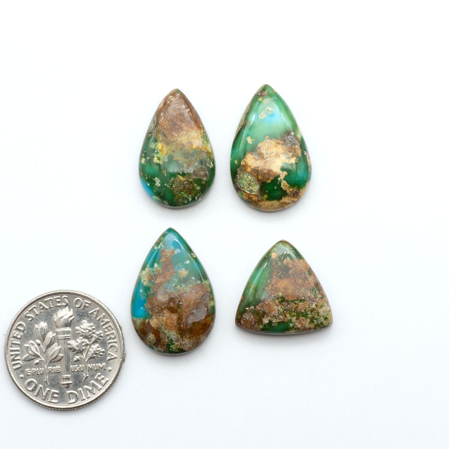 Sonoran Mountain Turquoise cabochons, blue-green color with natural matrix, polished stones on a white background, with a US dime for scale