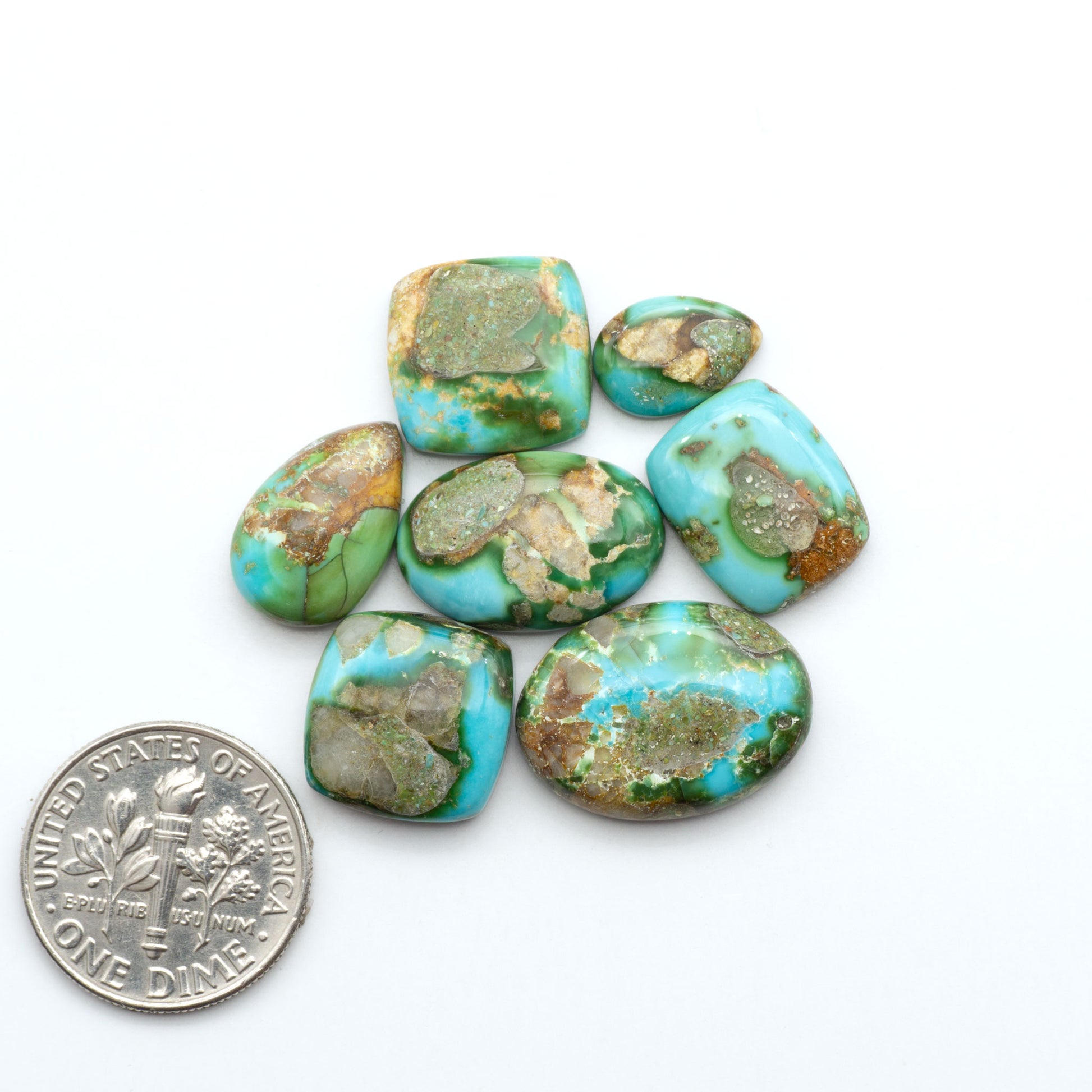 Sonoran Mountain Turquoise cabochons, blue-green color with natural matrix, polished stones on a white background, with a US dime for scale