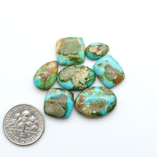 Sonoran Mountain Turquoise cabochons, blue-green color with natural matrix, polished stones on a white background, with a US dime for scale