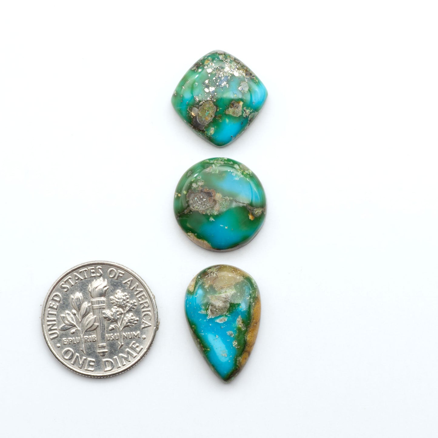 Sonoran Mountain Turquoise cabochons, blue-green color with natural matrix, polished stones on a white background, with a US dime for scale