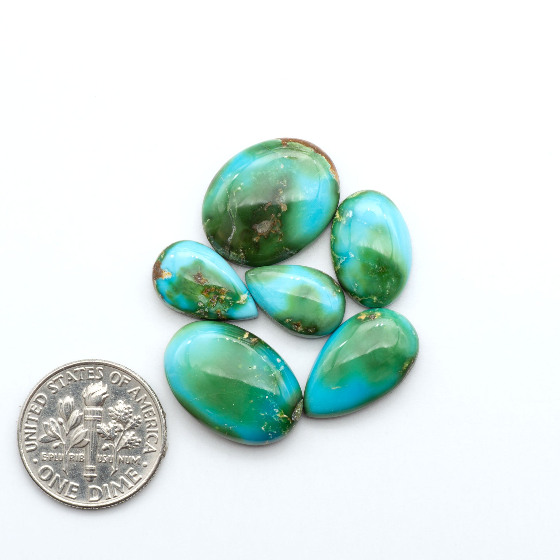 Sonoran Mountain Turquoise cabochons, blue-green color with natural matrix, polished stones on a white background, with a US dime for scale