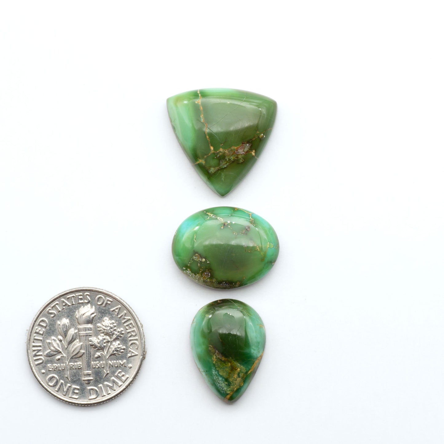 Sonoran Mountain Turquoise cabochons, blue-green color with natural matrix, polished stones on a white background, with a US dime for scale
